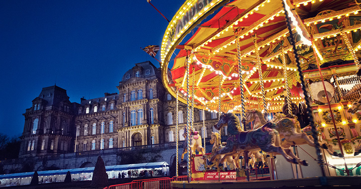 View of the Bowes Museum at dusk during the Christmas Market with carousel.